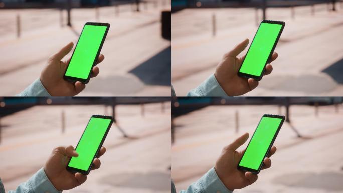 年轻男子使用绿色屏幕的手机