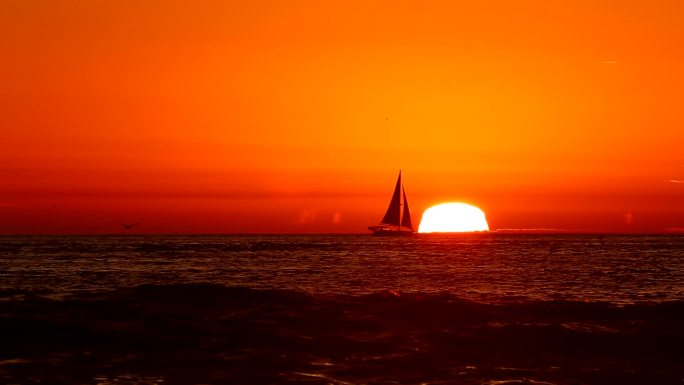 橙色日落时帆船行驶在海上