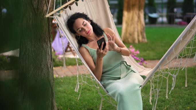女人在户外吊床上用智能手机上网
