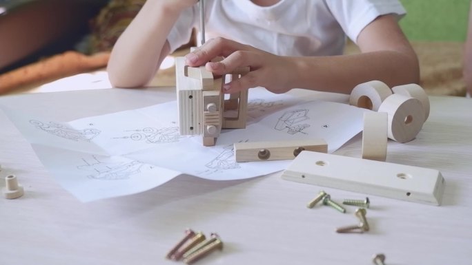 一个男孩用螺丝刀在组装一辆木制玩具车