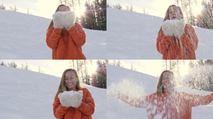 一名年轻女子站在雪地里用手吹雪。