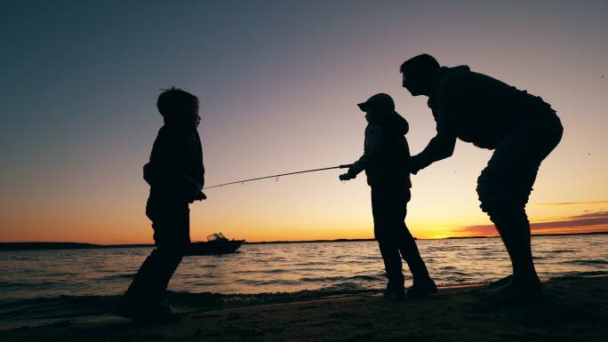 父亲正在帮助快乐的孩子们在湖里钓鱼