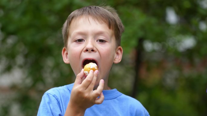 小男孩在户外满嘴吃东西的照片。