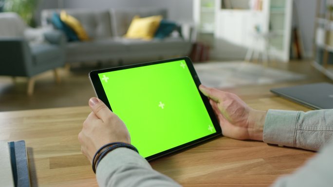 手持绿色模拟屏幕数字平板电脑观看的男子。