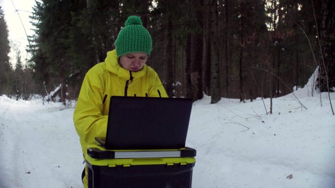 生态学家在冬季森林里用笔记本电脑工作