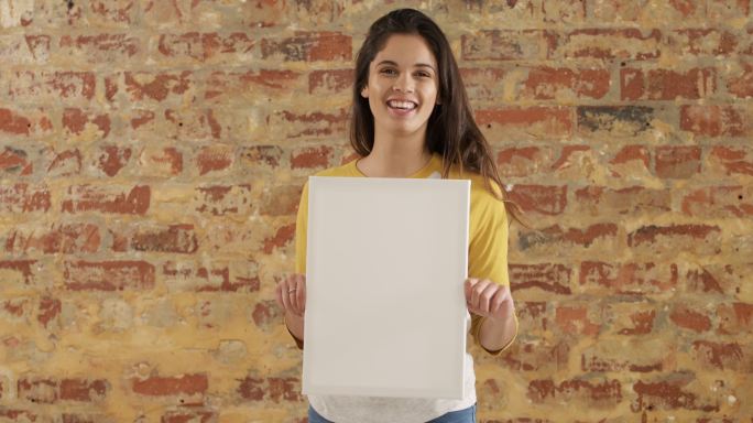 女子在砖墙上举着一个白板