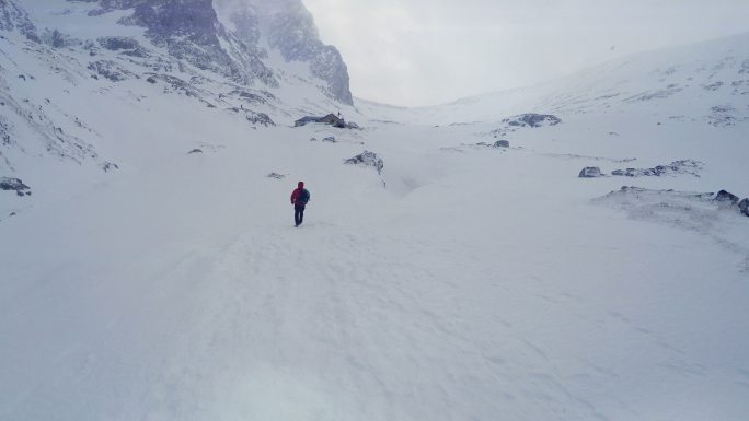 男子徒步穿越积雪覆盖的山谷，前往顶峰