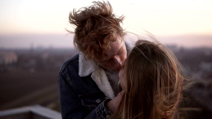 年轻的情侣在天空的城市景观背景下接吻