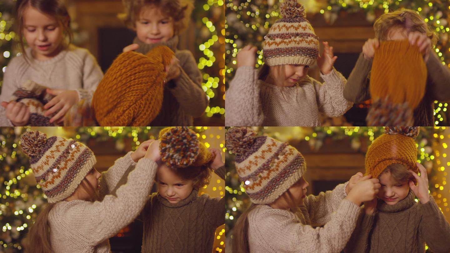 女孩帮助弟弟戴上带有绒球的针织棕色帽子