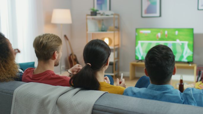 体育迷坐在沙发上观看电视上的重要足球比赛