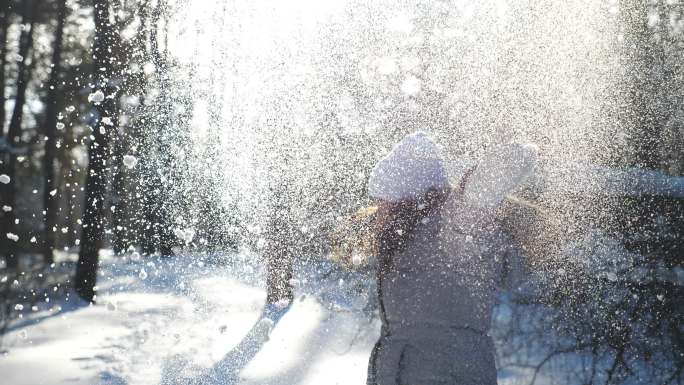 年轻快乐的女人穿着冬衣，扔着一把雪