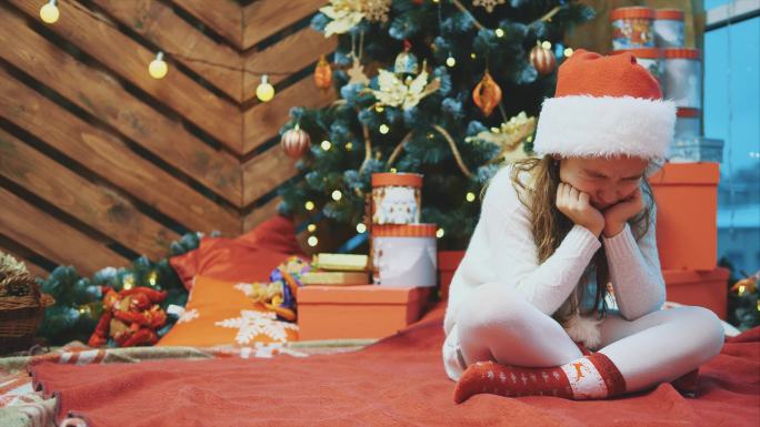 小女孩坐在圣诞背景上哭泣