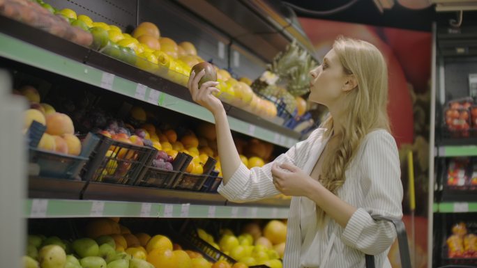 年轻女子在杂货店挑选成熟的芒果