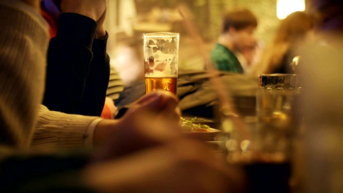 人们晚上坐在酒吧里喝啤酒。