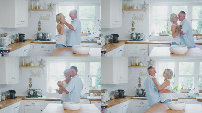 退休的浪漫老年夫妇在厨房里一起跳舞