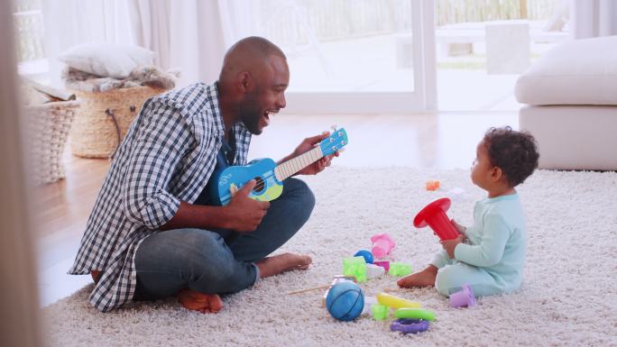 年轻父亲和儿子在客厅演奏四弦琴