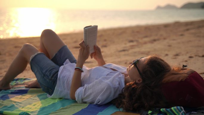 一位年轻女子正在海滩上看书