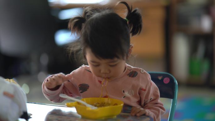可爱的亚洲宝宝在桌上吃面条