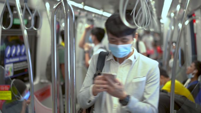 列车上的男子在高峰时间通过手机听音乐。