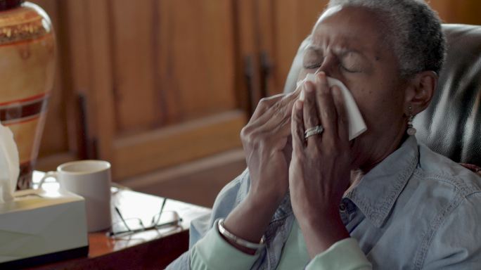 老年妇女打喷嚏，用面巾纸擤鼻涕
