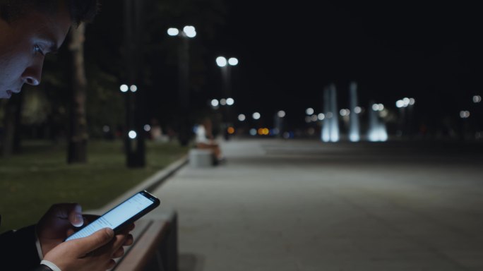 城市公园中一名男子在手机上浏览页面