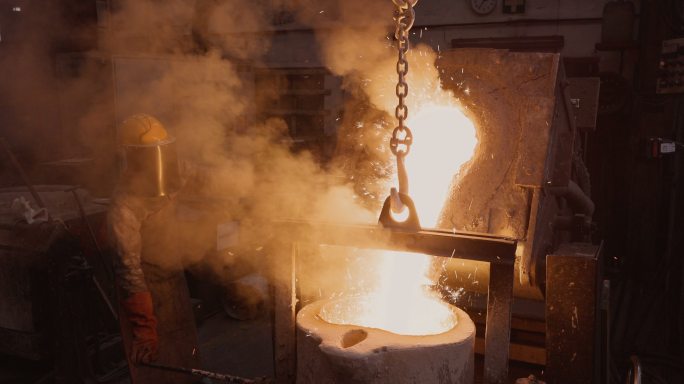 工人在一家铸钢厂将熔融金属从熔炼炉中倒出