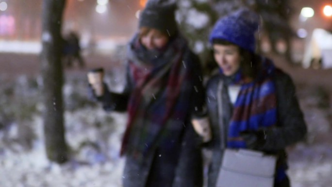 一群快乐的朋友手拿纸咖啡杯在雪地里散步