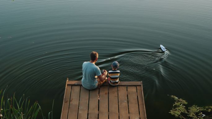爸爸和小儿子在湖上玩RC玩具快艇