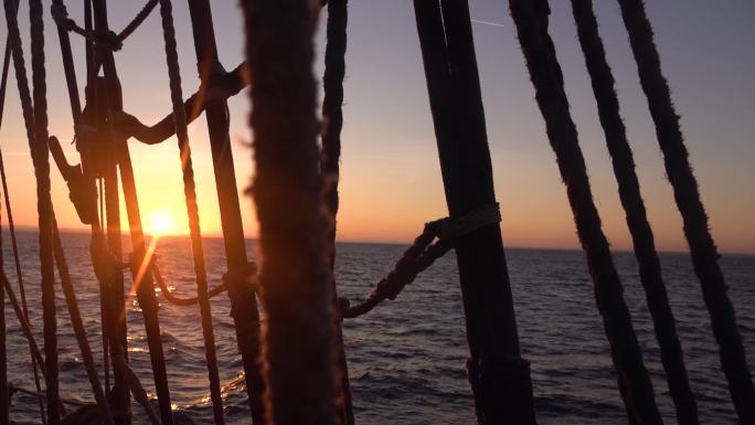 夕阳透过一艘旧帆船的护罩和索具。