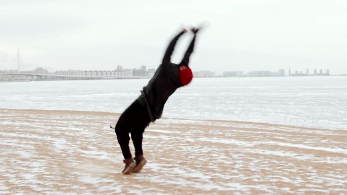 男子跑酷运动员在冰冻的湖岸上做后空翻
