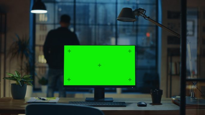 在办公室的木制办公桌上有绿色屏幕台式电脑