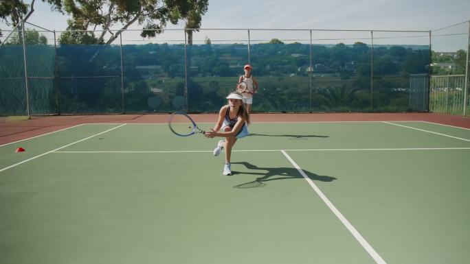 努力打网球的女孩在球场上练习