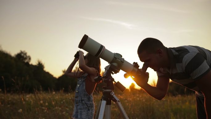 父亲和女儿用望远镜观察天空