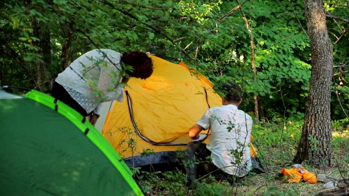 夫妻在落叶林中搭帐篷