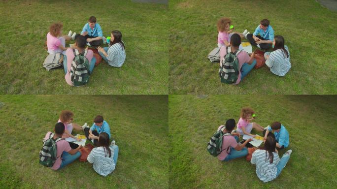 学生坐在户外的草地上集思广益