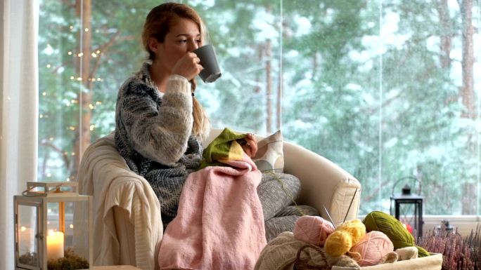 年轻女子在客厅里编织温暖的羊毛衫