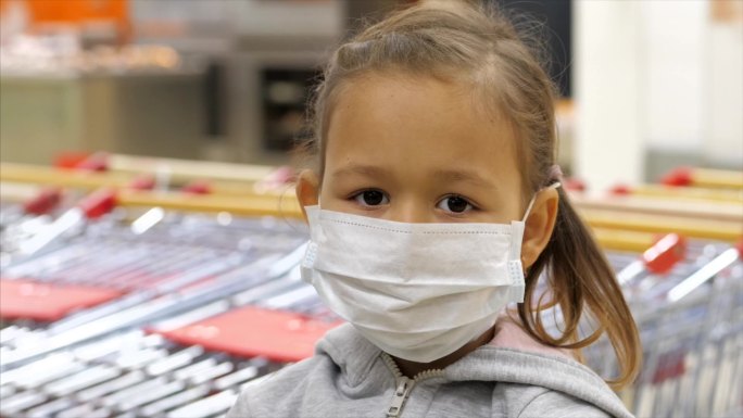 在超市里戴着医用口罩的小女孩