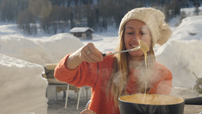 快乐的年轻女子在瑞士吃奶酪火锅