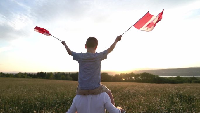 男孩骑在父亲肩上拿着加拿大国旗