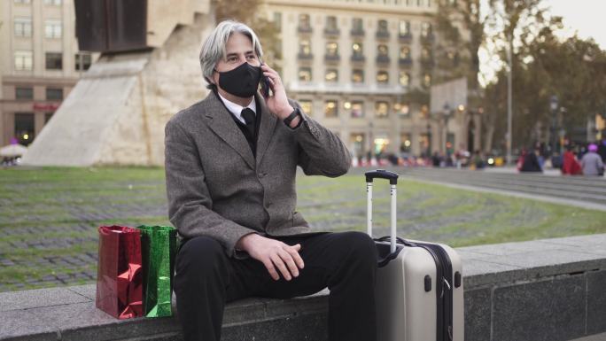 一个戴着口罩的男人在旅行中给家人打电话。