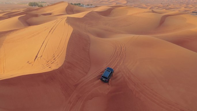 日落时一辆车在迪拜沙漠中行驶