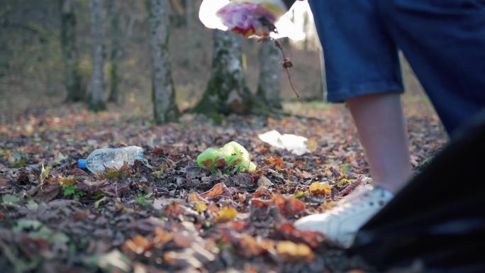 一个女人在落叶上收集脏垃圾