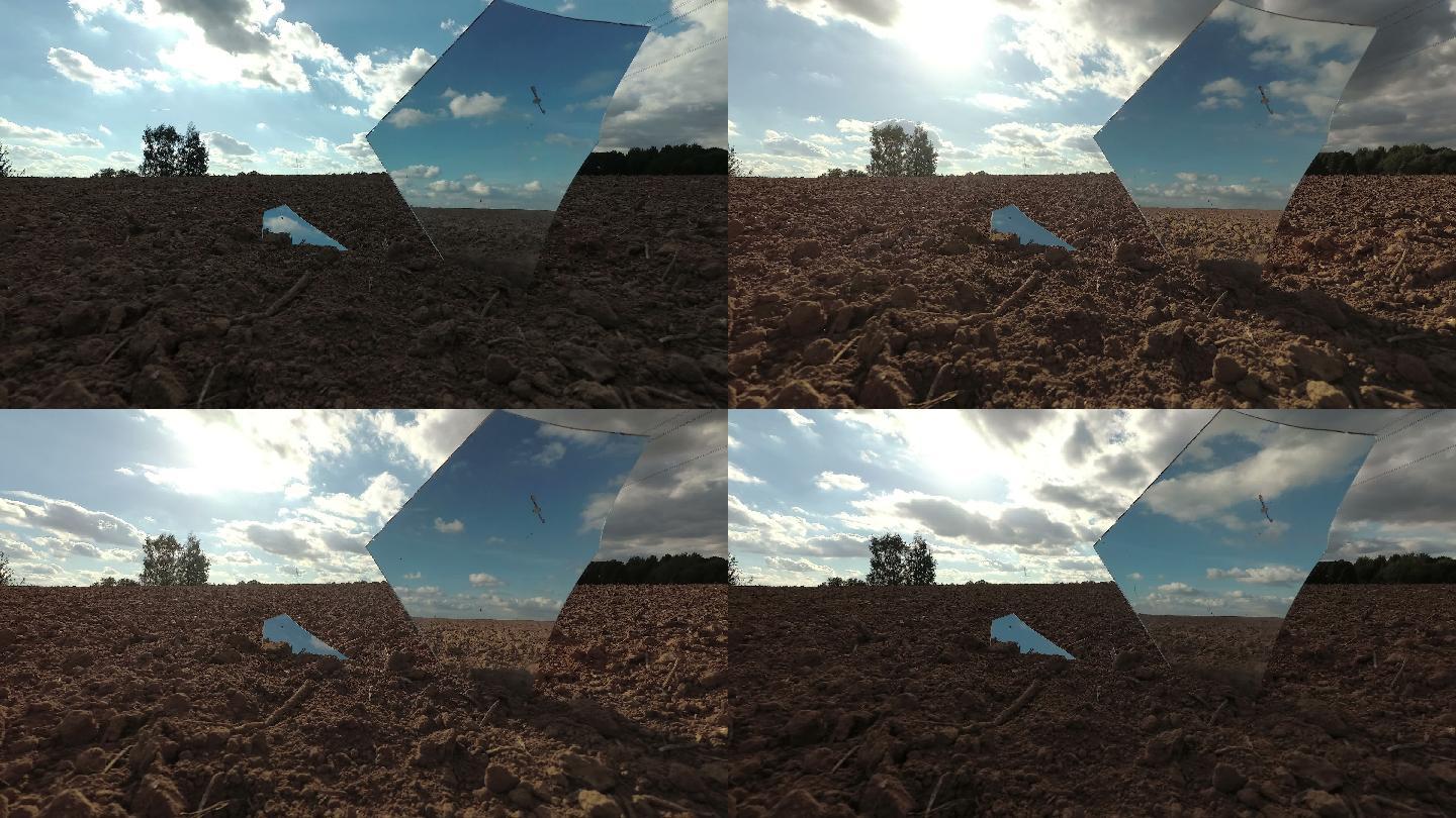 破碎的镜子碎片映着田野和云层