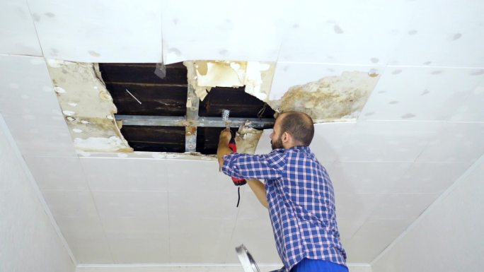 一名男子正在修理倒塌的天花板