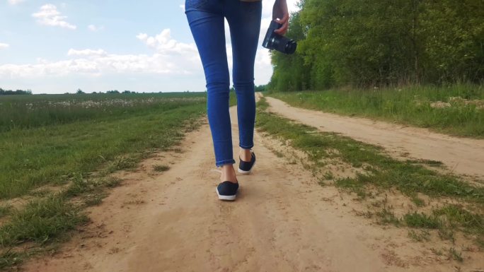一位美女的双腿在田野间的乡间小路上行走