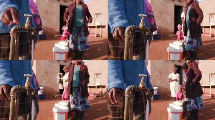 女性排队用塑料桶取水的特写镜头