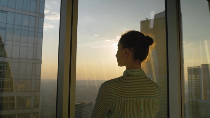 女人透过摩天大楼的窗户看城市景观