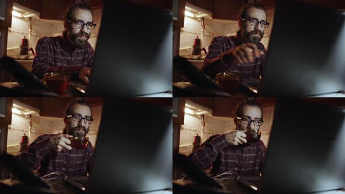 使用笔记本电脑时喝茶的男人