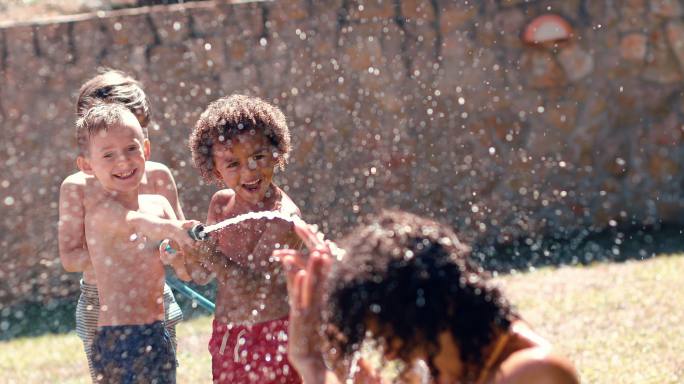 一群孩子用水管向母亲泼水