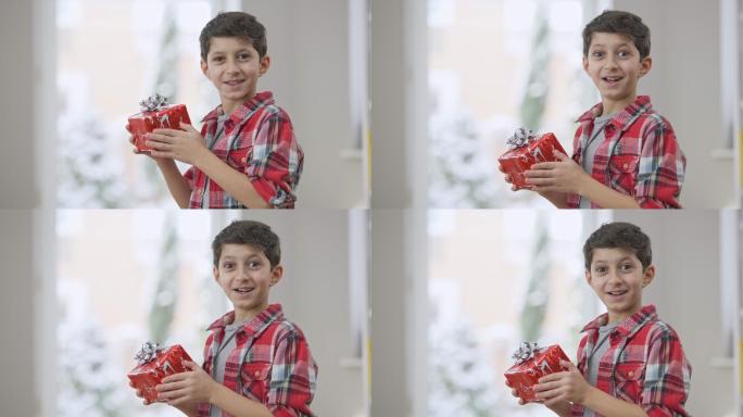 兴奋可爱的中东男孩摇着礼物看着相机